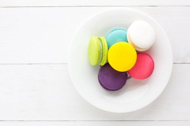 Beyaz ahşap arka plan üzerinde renkli Macaroons.