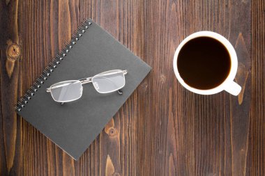 Beyaz kahve fincanı sade kahve, defter ve ahşap masa gözlük.