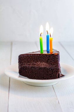 Beyaz plaka üzerinde mum ile çikolatalı kek.