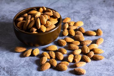 Masanın üzerinde ahşap kâse olan bademler. 