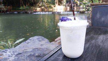 Dere yanında ahşap masada Hindistan cevizi yüzlü.