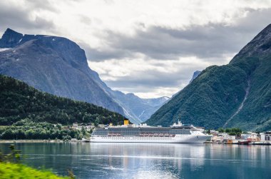 Arkasında dağlar ve yukarıda bulutlar ile bir Norveç fiyort üzerinde Yelkenli gemi