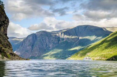Arkasında dağlar ve yukarıda bulutlar ile bir Norveç fiyort üzerinde Yelkenli gemi