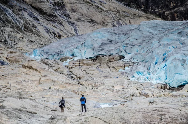 Nära utsikt över Nigardsbreens glaciär i Jostedal med två turister som tittar på glaciären — Stockfoto