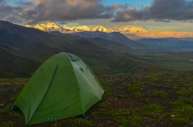 Denali Dağı'nın gün doğumu manzarası - Stony Dome'dan ön planda yeşil kamp çadırı ile altın saat boyunca alpenglow ile Mt Mckinley zirvesi.