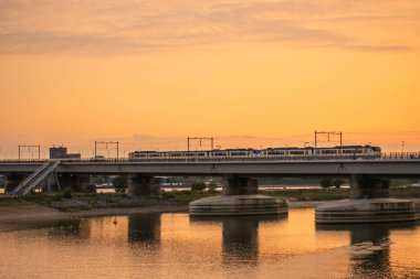 Gün batımında Hollanda treni köprüden geçiyor