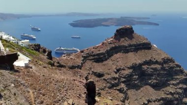 Sakin mavi suların üzerindeki Santorinis kayalıklarının çarpıcı hava manzarası, yolcu gemileri kalderada süzülürken, bu ikonik seyahat, tatil beldesi üzerine eşsiz bir perspektif sağlar.