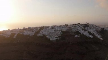 Çarpıcı insansız hava aracı görüntüleri, Santorini Tepesi 'nin beyaz bir köyünü okyanus manzaralı ve güzel bir günbatımı ile sergiliyor. Bu da burayı huzur ve rüya gibi bir cennet arayan gezginler için ideal bir yer haline getiriyor.