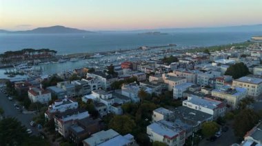 San Francisco marinasının nefes kesici manzarası üzerinde nefes kesici bir hava görüntüsü, canlı şehir hayatı ve sakin sularla birlikte gün batımında, Alcatraz adası hapishanesi uzak mesafede..