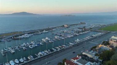 San Fransisco marinası üzerindeki göz kamaştırıcı görüntüler, alacakaranlıktaki büyüleyici alacakaranlıkta Alcatraz adasının gölgesinde parıldayan suyla çevrili yatlar ve teknelerle dolu.