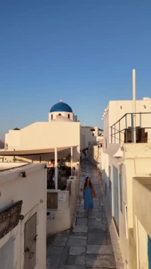 Santorini 'de bulunan sevimli ve büyüleyici bir caddenin nefes kesici ve manzaralı manzarası dikkat çeken sakin ve huzurlu bir atmosferle birlikte çarpıcı bir mavi kubbe kilisesi sergiliyor.