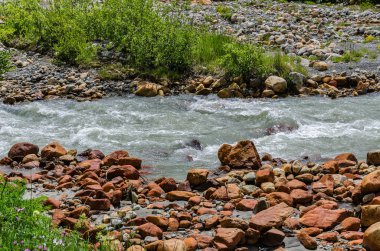 Georgia, Svaneti, Ushguli 'den Shkhara Buzulu 'na yolculuk. İnanılmaz kırmızı taşlar ve su akışı ile dağ Nehri