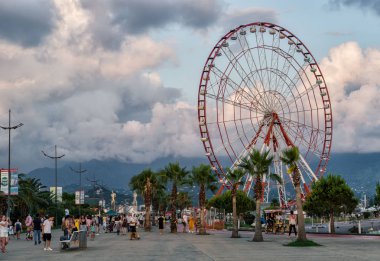 Batum,Acara,Gürcistan - 06 Temmuz 2019, Batum seti, batan güneşin ışınlarında dönme dolap, alışılmadık renkli bulutlar