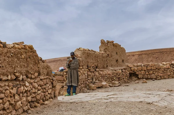 Maroko, Kasbah AIT Ben Haddou nedaleko Ouarbingu v pohoří Atlas, 28. březen 2018, marocký muž opřený o zeď a dívá se na mobilní telefon. Seznam světového kulturního dědictví UNESCO — Stock fotografie