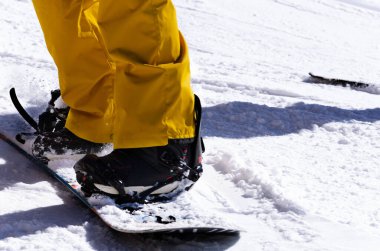 Güneşli bir günde kayak botları giymiş ve dağ yamacında kayak yapan bir sporcunun yakın çekimi. Kış sporları