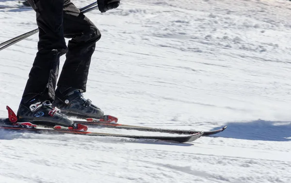Güneşli bir günde kayak botları giymiş ve dağ yamacında kayak yapan bir sporcunun yakın çekimi. Kış sporları — Stok fotoğraf