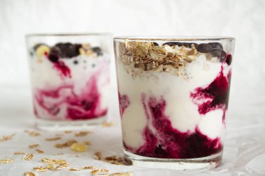 Çilek ve müsli ile dondurma. Beyaz bir arka plan üzerinde kuş üzümü, berry reçeli ve müsli ile bir bardak dondurma. Close.