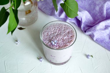 Berry milkshake. Beyaz bir arka plan üzerinde yaban mersini ile Milkshake, leylak çiçekleri ile dekore edilmiştir. Provence tarzı