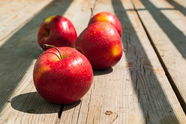 Ripe red apples on a sunny day on a wooden old table. Close-up