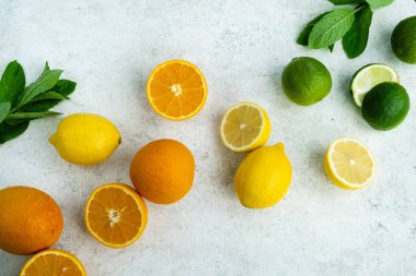 Hafif arkaplanda taze narenciye meyveleri. Limon, limon, portakal ve nane. Yaz diyeti, C vitamini, bağışıklık sistemi güçlendirici. Üst manzara, düz uzanma
