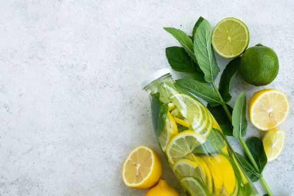 Lemonade or mojito in glass bottle. Refreshing summer drink with lemon, lime and mint on kitchen table. Vitamin C, Immunity system booster, detox and diet. Top view, flat lay, copy space