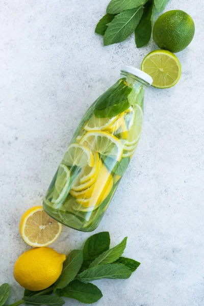 Mojito or lemonade in glass bottle. Summer drink with fresh lemon, lime and mint on table. Vitamin C, Immunity system booster, detox and diet. Top view, flat lay, vertical