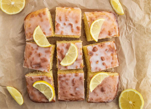 Sweet lemon cake on baking paper. Pieces of cake with zest, decorated sugar icing. Top view