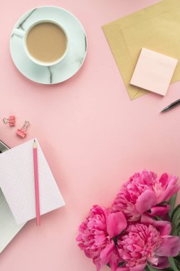 Merkez ofis masası. Dizüstü bilgisayarı, not defteri, çiçekleri ve kahvesi olan bir kadın işyeri. Pastel renkte kompozisyon. Üst görünüm, düz görünüm, kopyalama alanı, dikey