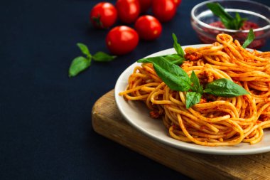 Koyu mavi masadaki bir tabakta spagetti bolonez. Domates soslu İtalyan makarnası ve kıyma. Kapat, boşluğu kopyala
