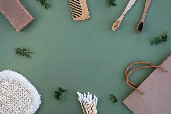 Yeşil arka planda plastiksiz banyo aksesuarları. Bambu diş fırçaları, pamuk tomurcukları, tarak, doğal sabun, bez ve çanta. Sıfır atık, çevre dostu konsept. Üst görünüm, düz görünüm, kopyalama alanı, çerçeve