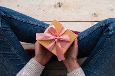 Kadının elinde pembe kurdeleli hediye paketi var. Tatil, hediyeler ve indirim konsepti. Kapat, üst görünüm