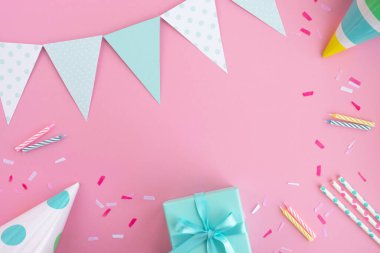 Doğum günü partisi geçmişi. Pastel pembe ve nane renginde kompozisyon. Doğum günü şapkaları, hediye kutuları, parti bayrakları, pipet, konfeti ve mumlar. Üst görünüm, düz görünüm, kopyalama alanı