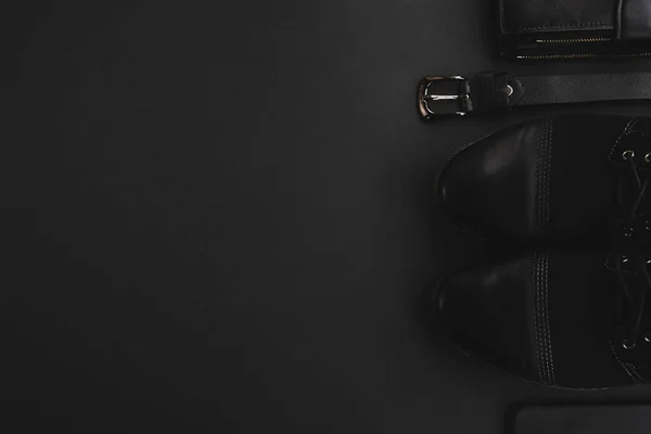 Siyah arka planda erkek aksesuarları. Ayakkabılar, deri kemer, cüzdan ve akıllı telefon. Alışveriş, moda, satış konsepti. Üst görünüm, düz görünüm, kopyalama alanı