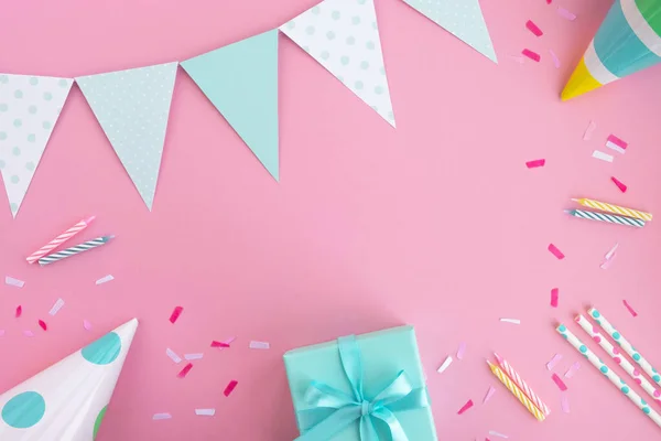 Doğum günü partisi geçmişi. Pastel pembe ve nane renginde kompozisyon. Doğum günü şapkaları, hediye kutuları, parti bayrakları, pipet, konfeti ve mumlar. Üst görünüm, düz görünüm, kopyalama alanı