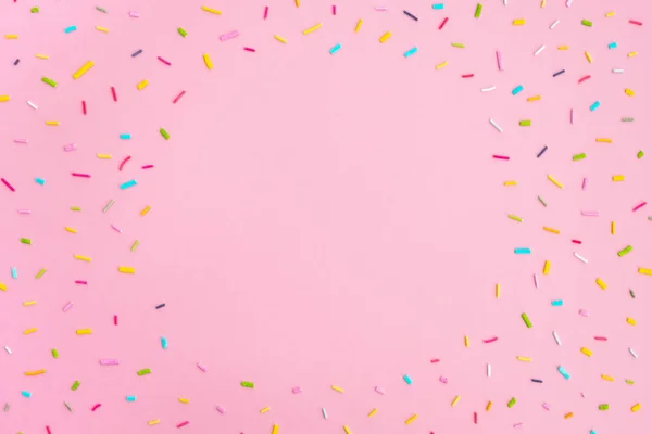 Pastel pembe arka planda tatlı renkli konfeti. Minimum trend kompozisyonu. Doğum günü partisi, kutlama, tasarım modeli. Üst görünüm, çerçeve, düz görünüm, boşluğu kopyala