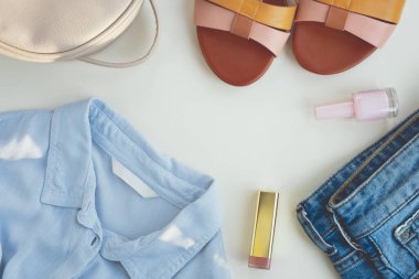 Beyaz arka planda kadın kıyafetleri ve aksesuarları. Ayakkabılar, bluz, kot şort, el çantası ve kozmetik. Alışveriş, satış konsepti. Üst manzara, düz uzanma