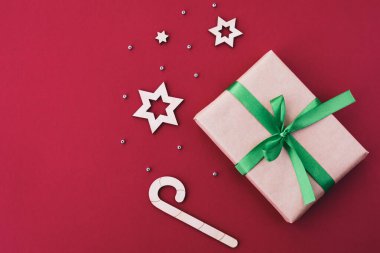 Noel ve Yeni Yıl kompozisyonu. Kırmızı parlak bir arka planda hediye kutusu ve şenlikli bir dekor. Üst görünüm, düz görünüm, kopyalama alanı