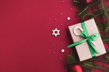 Noel ve Yeni Yıl kompozisyonu. Hediyeler, noel baloları, köknar ağacı, kırmızı parlak bir arka planda şenlik dekoru. Üst görünüm, düz görünüm, kopyalama alanı