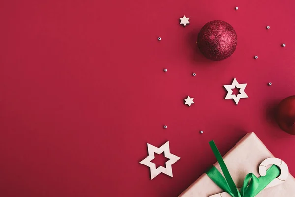 Noel ve Yeni Yıl kompozisyonu. Hediye kutusu, noel baloları, kırmızı parlak arka planda şenlik dekorasyonu. Üst görünüm, düz görünüm, kopyalama alanı