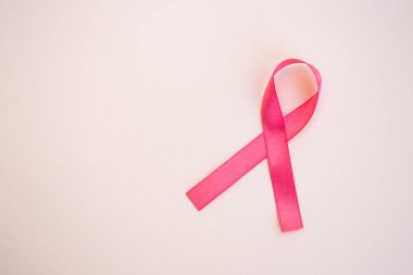 Açık pembe arka planda pembe göğüs kanseri farkındalığı kurdelesi. Tıp ve sağlık konsepti, kadın sağlığı. Boşluğu kopyala