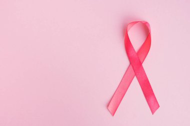 Açık arkaplanda pembe göğüs kanseri farkındalığı kurdelesi. Tıp ve kadın sağlığı konsepti. Boşluğu kopyala, üst görünüm