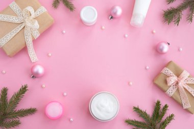 Kozmetik ürünler, hediye kutuları ve açık pembe arka planda festival dekorasyonu. Noel ve yeni yıl hediyeleri, güzellik ve cilt bakımı. Üst görünüm, düz görünüm, kopyalama alanı, çerçeve