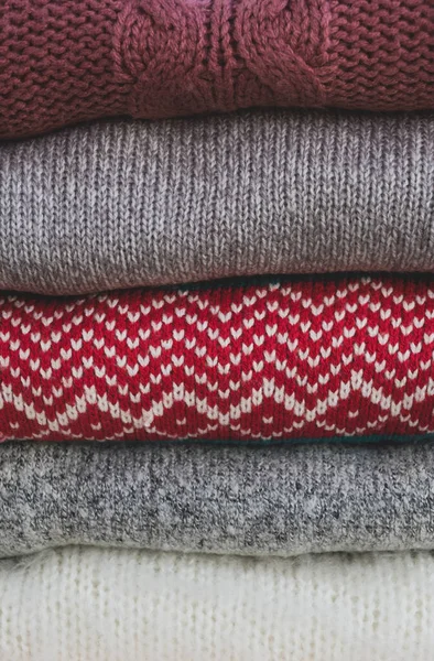 Bir yığın örülmüş süveter pastel renkler. Sıcak sonbahar ya da kışlık giysiler. Yakın, dikey, doku