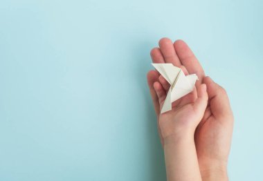 Adam ve çocuk elleri açık mavi arka planda beyaz güvercin kuşu tutuyor. Uluslararası barış, umut ve özgürlük günü. Üst görünüm, alanı kopyala