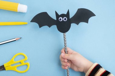 Cadılar Bayramı el yapımı dekor. Çocuk kağıt sopa yapıyor. Yapışkan oyuncak gözler. Beşinci adım. Üst manzara, düz uzanma