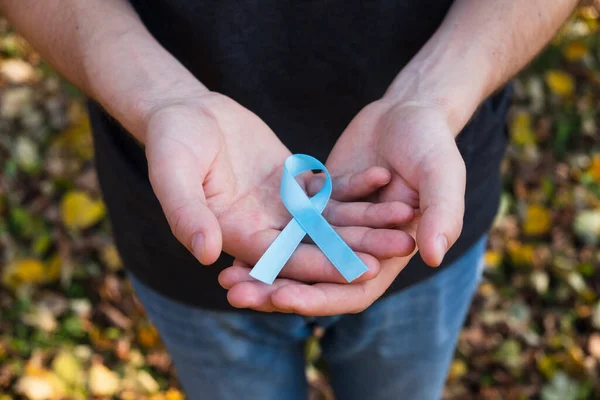 Mãos Homem Segurar Azul Fita Consciência Câncer Próstata Fundo Folhagem — Fotografia de Stock