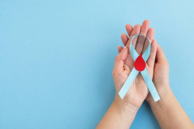 Kadınların elleri, kırmızı kan damlasıyla açık mavi kurdele farkındalığı taşır. Dünya Diyabet Günü. Üst görünüm, alanı kopyala