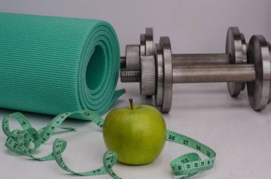 Dambıllı yeşil elma, bir halı ve bir bant. Kadın fitness.