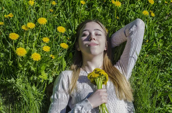 La fille se trouve dans une clairière avec un bouquet de pissenlits — Photo