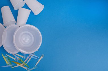Mavi arkaplandaki tek kullanımlık sofra takımı. Kavram: ekoloji, çevre kirliliği. Yemek üretimi. 
